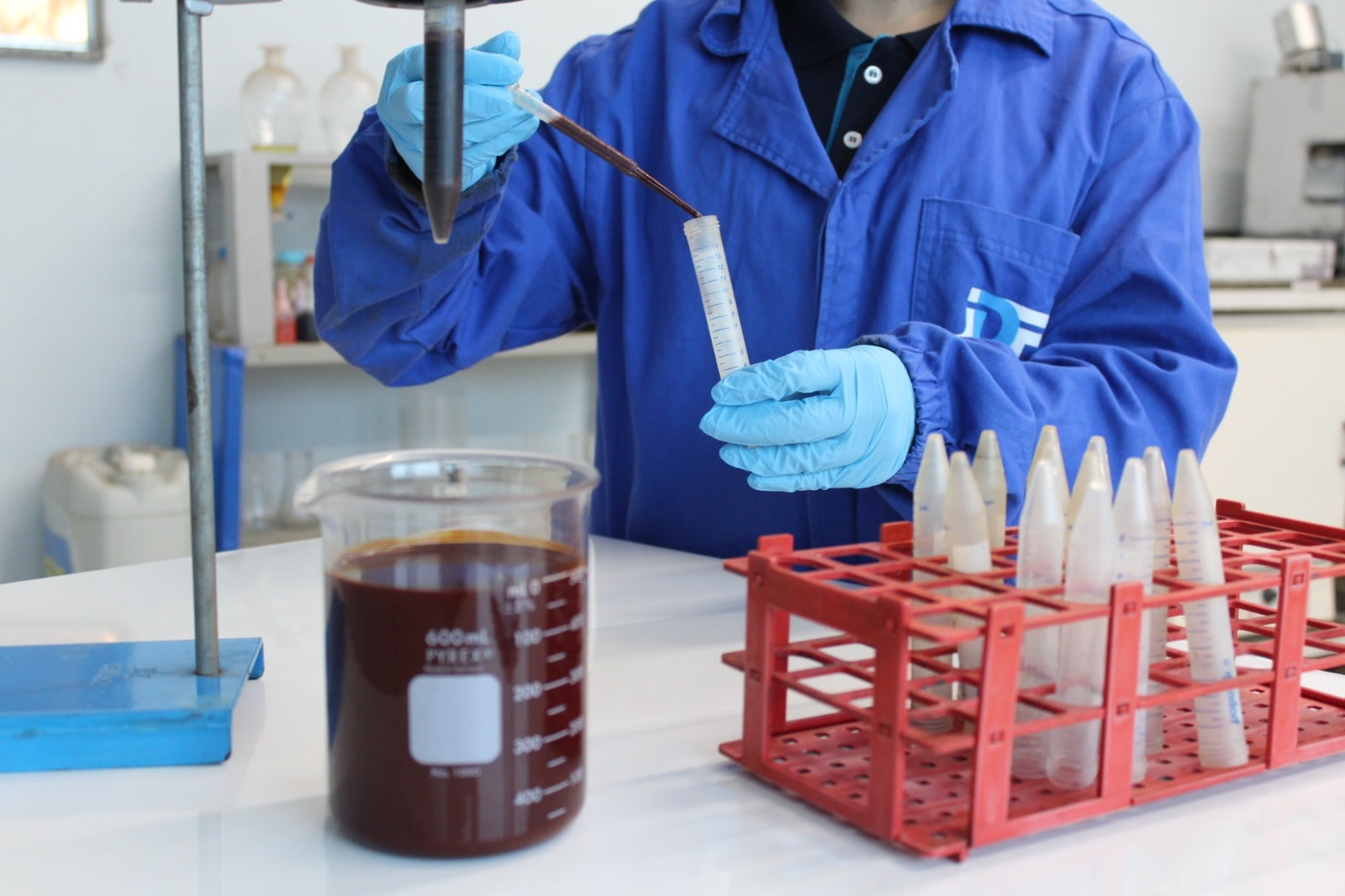 Profissional manipulando amostra líquida em bancada de laboratório com materiais de análise